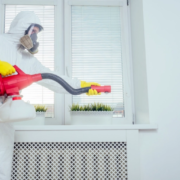 personne en combinaison de protection vaporisant un produit dans une chambre