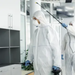2 personnes en combinaison de protection vaporisant un produit sur des murs